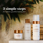 Three skincare bottles and jars from Young Living are displayed on a stone surface with a warm, textured background and green leaves. The products include a small jar, a toner bottle, and a foaming cleanser bottle, all in white with metallic copper caps.