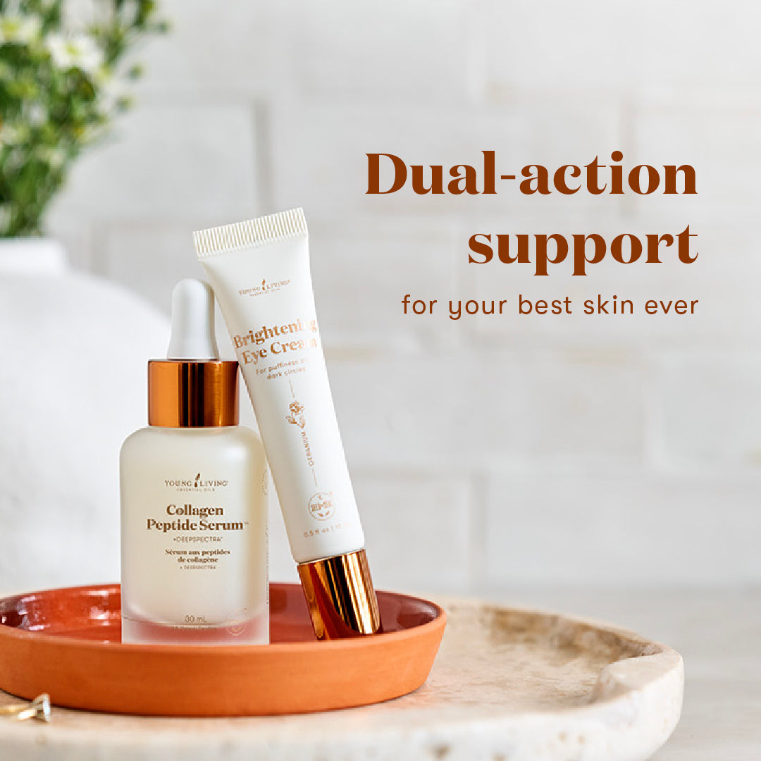 Two skincare products from Young Living are displayed on a terracotta dish against a bright, soft-focus background. The products are the Collagen Peptide Serum in a frosted glass dropper bottle with a gold cap, and the Brighten Eye Cream in a white tube with a gold cap.