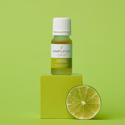 Bottle of 'Simplified' amber mead on a green block with a lime wedge on a green background