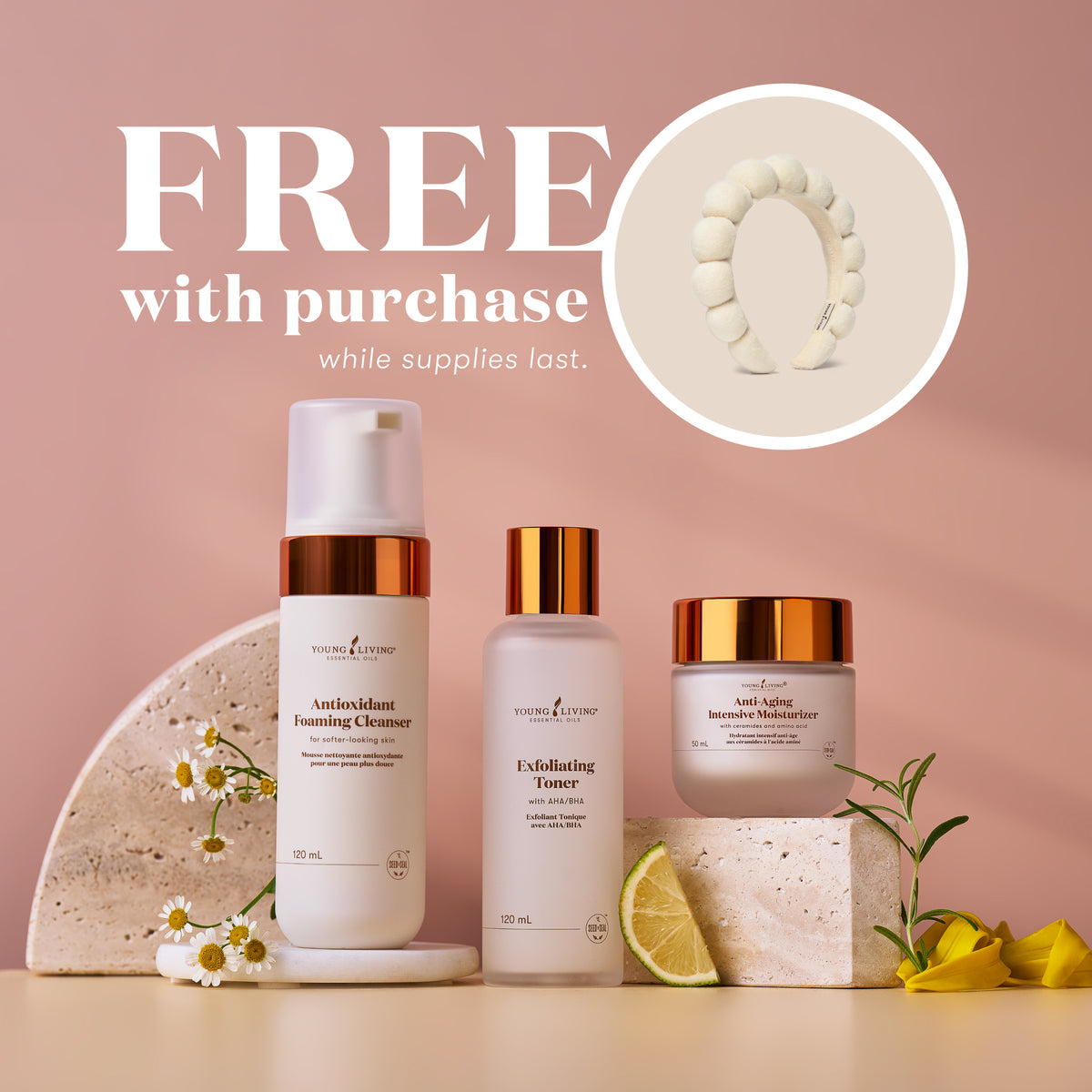 Three skincare products are displayed on a beige surface against a dusty pink background, with promotional text reading 'FREE with purchase while supplies last.' and a circular inset showing a white headband.